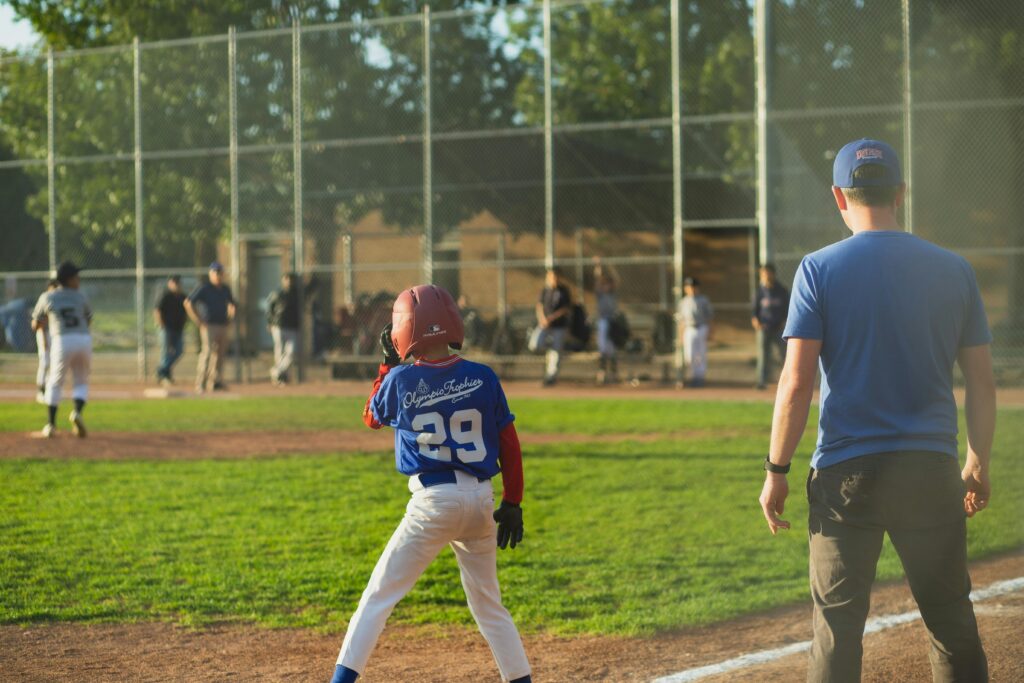 Youth baseball game with players and coach in action on a sunny field.