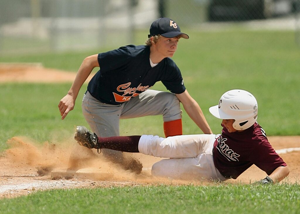 Exciting moment of young players sliding and tagging in a youth baseball game.