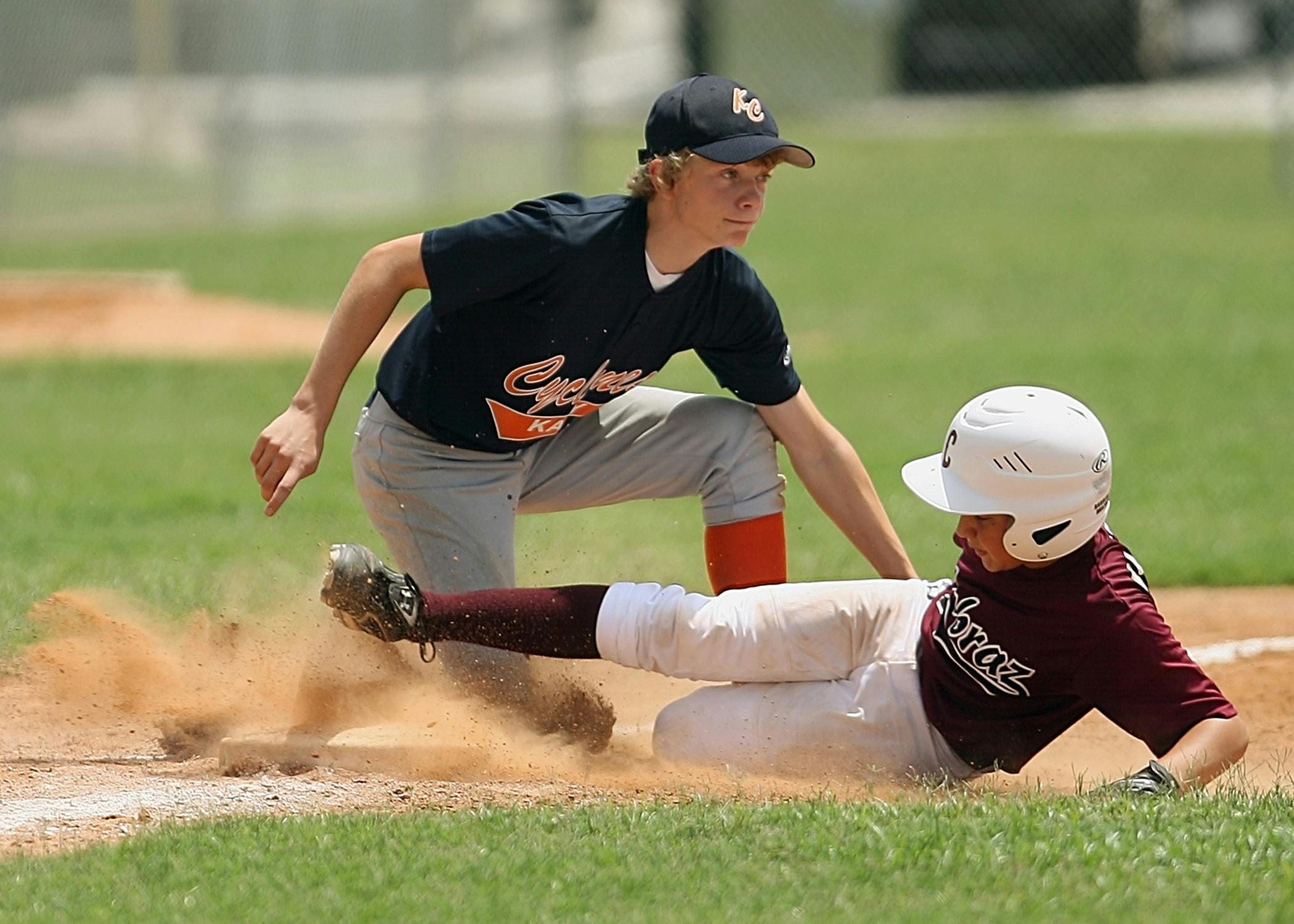 Exciting moment of young players sliding and tagging in a youth baseball game.